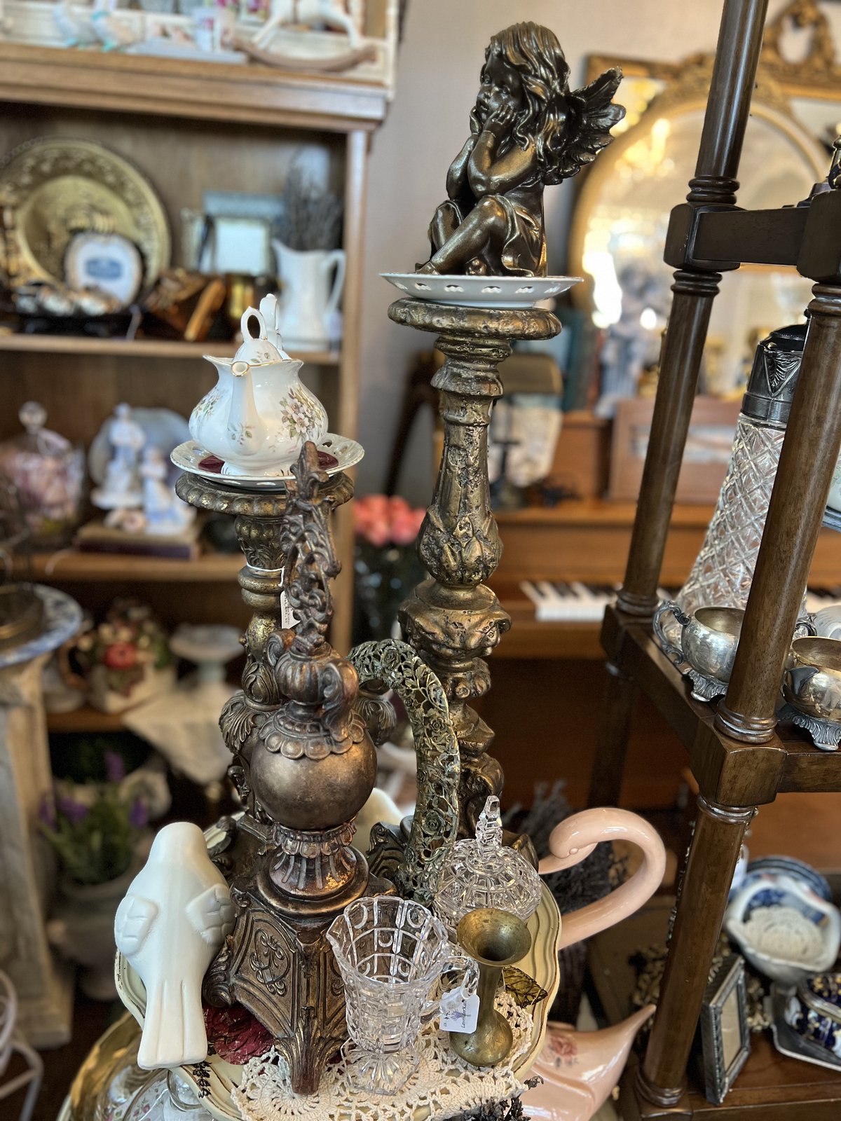 Bronze cherub figurine among porcelain teacups and candlesticks