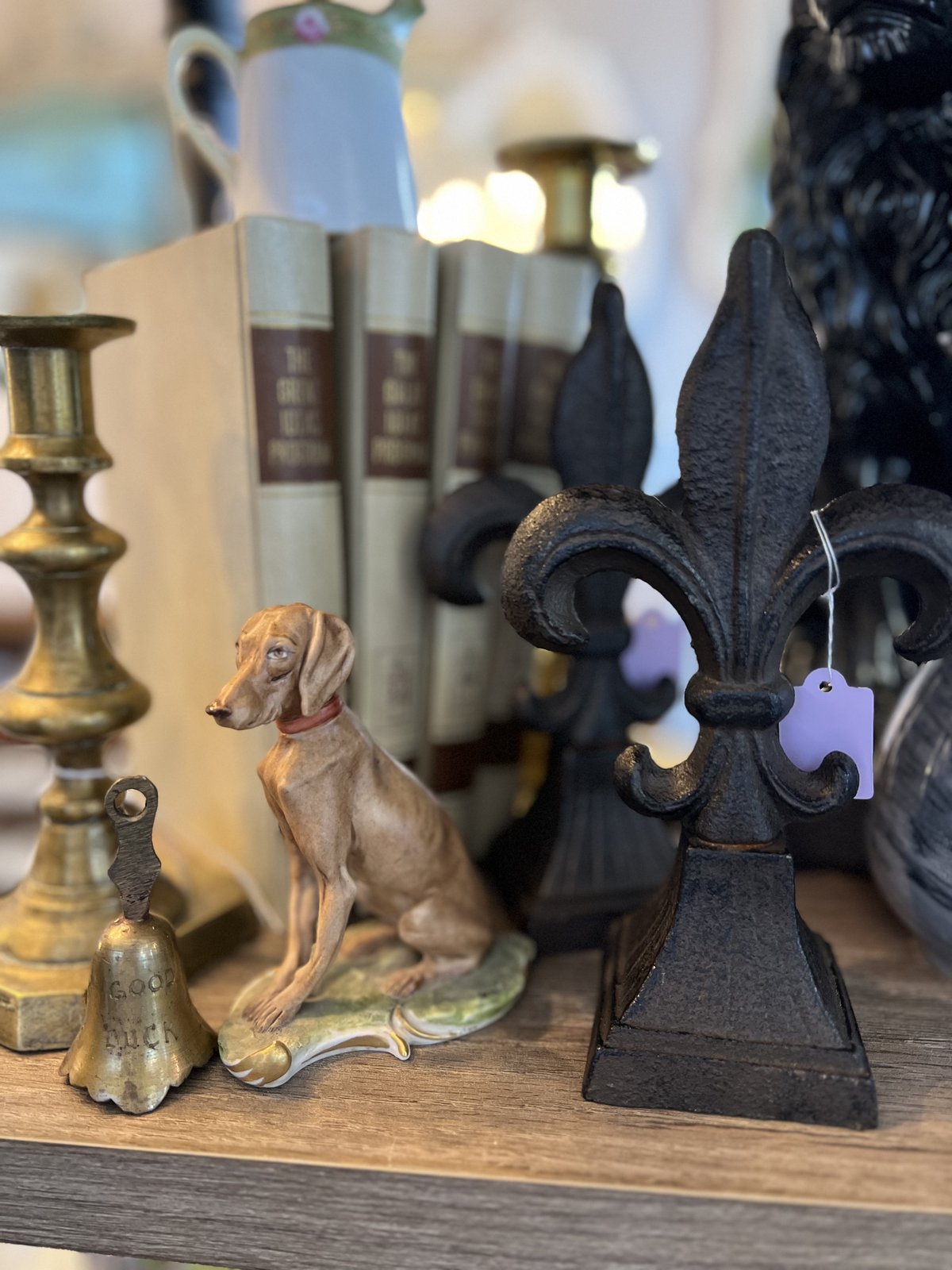 Porcelain hunting dog figurine among brass candlesticks